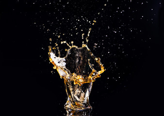 whiskey with splash on black background, brandy in a glass