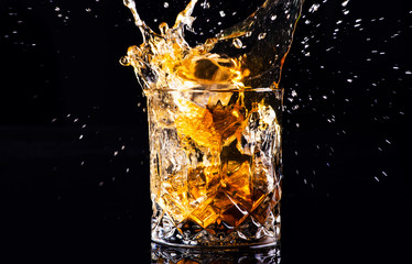 whiskey with splash on black background, brandy in a glass