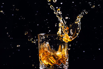 whiskey with splash on black background, brandy in a glass