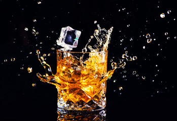 whiskey with splash on black background, brandy in a glass