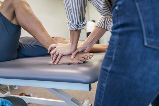 Midsection of physiotherapist giving foot massage to a man in clinic
