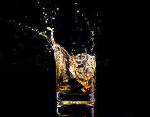 whiskey with splash on black background, brandy in a glass