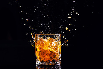 whiskey with splash on black background, brandy in a glass