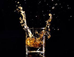 whiskey with splash on black background, brandy in a glass