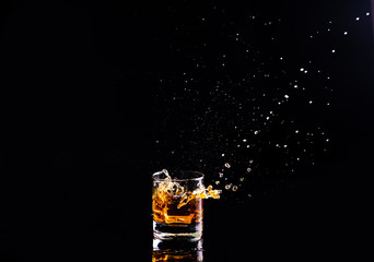 whiskey with splash on black background, brandy in a glass