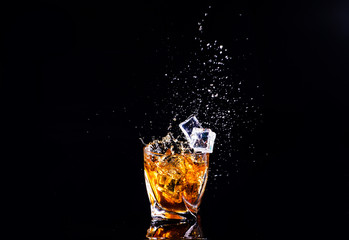 whiskey with splash on black background, brandy in a glass