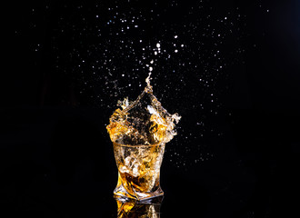 whiskey with splash on black background, brandy in a glass
