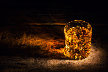 whiskey with ice cubes on wooden background