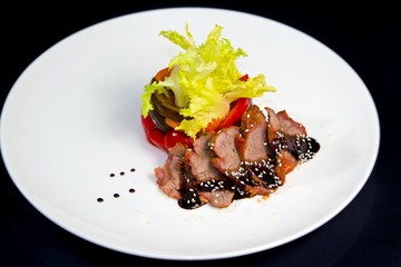 slices of smoked meat, served with garnish of fresh salad, grilled paprika and eggplant, black background food menu