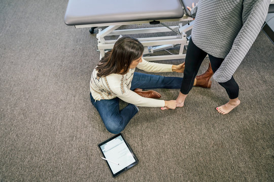 High angle view of physiotherapist examining patient's leg in clinic