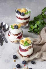 Granola, blueberry and banana greek yogurt parfaits in mason jars. Healthy breakfast. A light grey concrete background. Copy space.