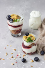 Granola, blueberry and banana greek yogurt parfaits in mason jars. Healthy breakfast. A light grey concrete background. Copy space.