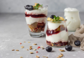 Granola, blueberry and banana greek yogurt parfaits in mason jars. Healthy breakfast. A light grey concrete background. Copy space.