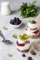 Granola, blueberry and banana greek yogurt parfaits in mason jars. Healthy breakfast. A light grey concrete background. Copy space.