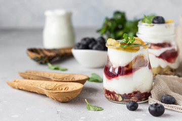 Granola, blueberry and banana greek yogurt parfaits in mason jars. Healthy breakfast. A light grey concrete background. Copy space.