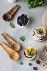 Granola, blueberry and banana greek yogurt parfaits in mason jars. Healthy breakfast. A light grey concrete background. Copy space.