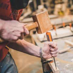 Manual processing of wood in the carpentry workshop - the master works with a chisel