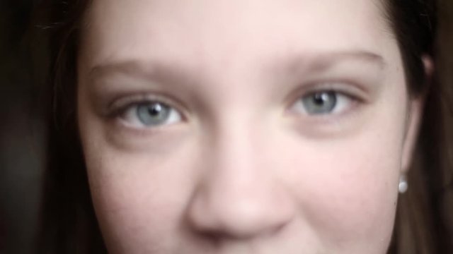portrait of a young cute caucasian girl looking into the camera and closing her eyes close up. girl with poor eyesight focus and to squint