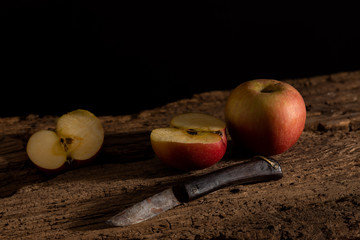 dark still life of apples and knife