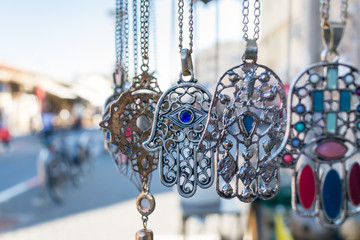 Close-up of Hamsa, also known as Fatima Hand or Hand of God necklace, pending on a flea market in Tel Aviv-Jaffa, Israel. Metal protection amulet. 