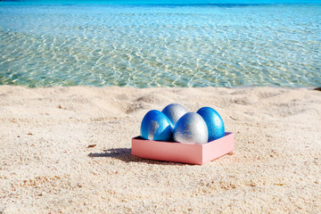 Fototapeta na wymiar Easter color eggs on the beach near the ocean