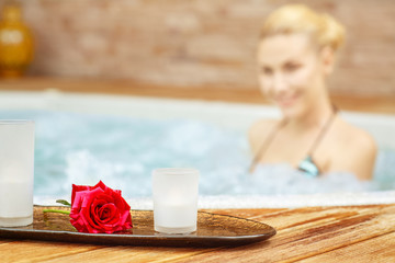 SPA in details. Selective focus on a plate with candles and a flower put near a Jacuzzi where SPA center client is relaxing