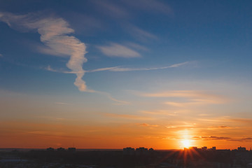 Fototapeta premium Sun rising over town skyline. Dramatic cityscape