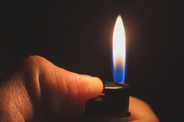 Hand igniting lighter on black background. Concept of memory of tragic events