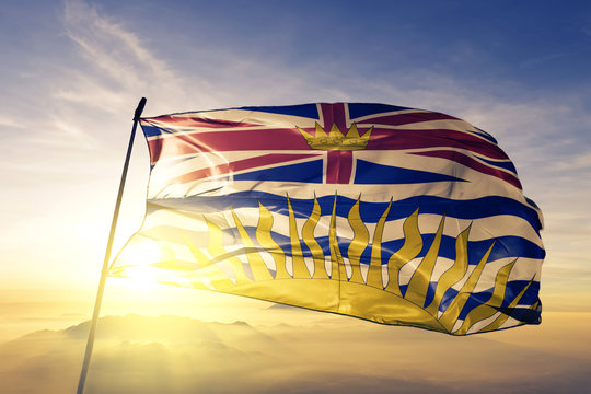 British Columbia province of Canada flag waving on the top sunrise mist fog