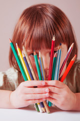 Concept: the world is colorful and wonderful. Humorous photo of great artist. Cute little child girl with colored pencils.