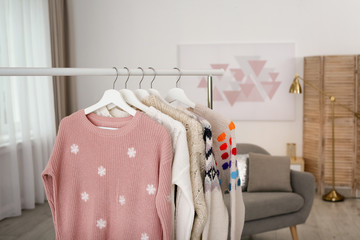 Wardrobe rack with stylish warm clothes indoors. Space for text