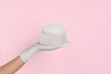 Doctor holding silicone implants for breast augmentation on color background, space for text....