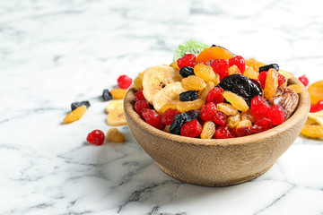 Bowl with different dried fruits on marble background, space for text. Healthy lifestyle