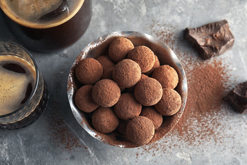 Bowl with tasty chocolate truffles on grey background, top view
