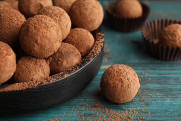 Plate of chocolate truffles on wooden background, closeup