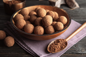 Plate with chocolate truffles on wooden background