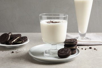 Glass with milk and chocolate cookies on table against grey background