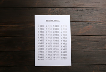 Answer sheet on wooden background, top view