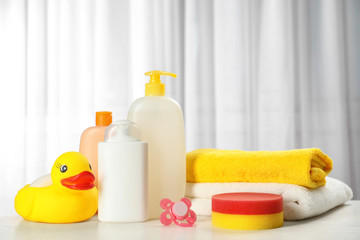 Baby cosmetic products, toy and towels on table indoors