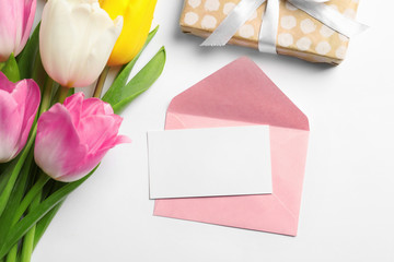 Flat lay composition of tulips and blank card on white background, space for text. International Women's Day