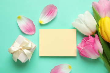 Flat lay composition of tulips and blank card on color background, space for text. International Women's Day