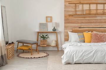 Fototapeta na wymiar Stylish room interior with comfortable bed near wooden wall