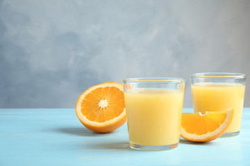 Glasses with orange juice and cut fruit on table, space for text
