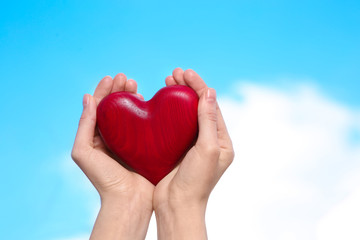 Woman holding decorative heart in hands on color background, space for text