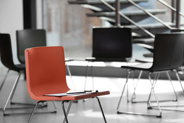 Red chair with clipboard in office prepared for group therapy. Meeting room interior