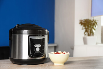 Modern multi cooker and ingredients on table indoors, space for text