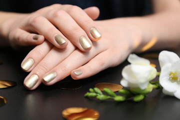 Obraz na płótnie Canvas Woman with golden manicure on black table, closeup. Nail polish trends