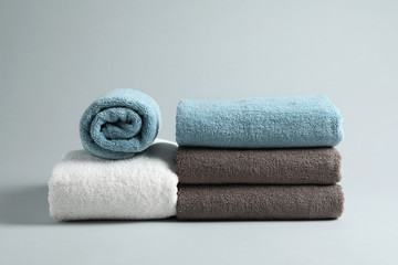 Fresh fluffy folded towels on grey background