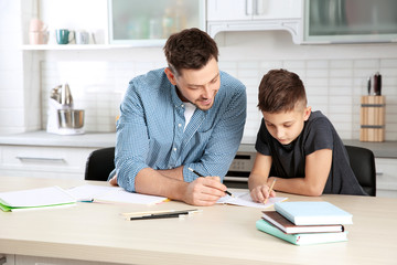 Dad helping his son with homework in kitchen
