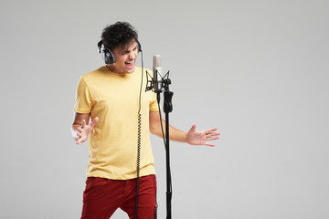 Portrait of rock singer man in studio professional headphones keeping static mic, sings a song...